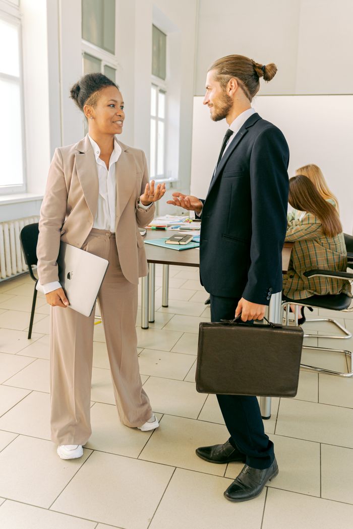 Business professionals conversing in a bright and airy workplace setting.