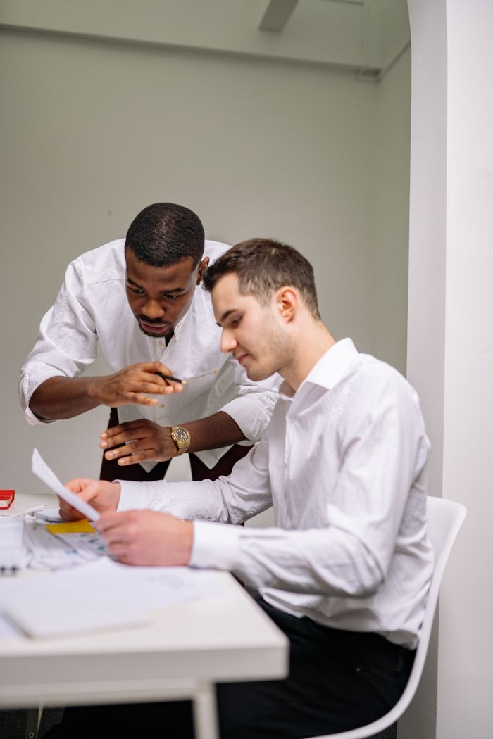 Two business professionals in a modern office engaged in a paper discussion.