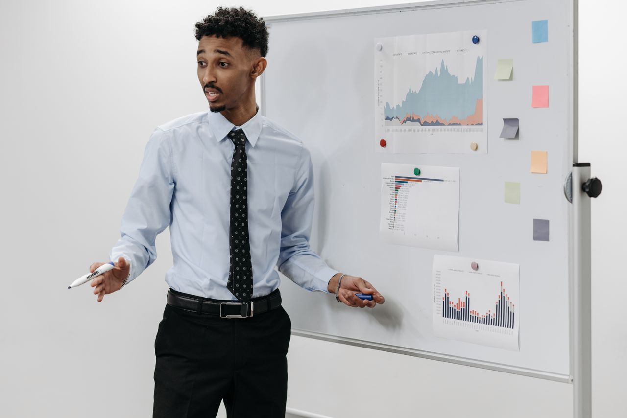 Man delivering a business presentation with charts on a whiteboard.